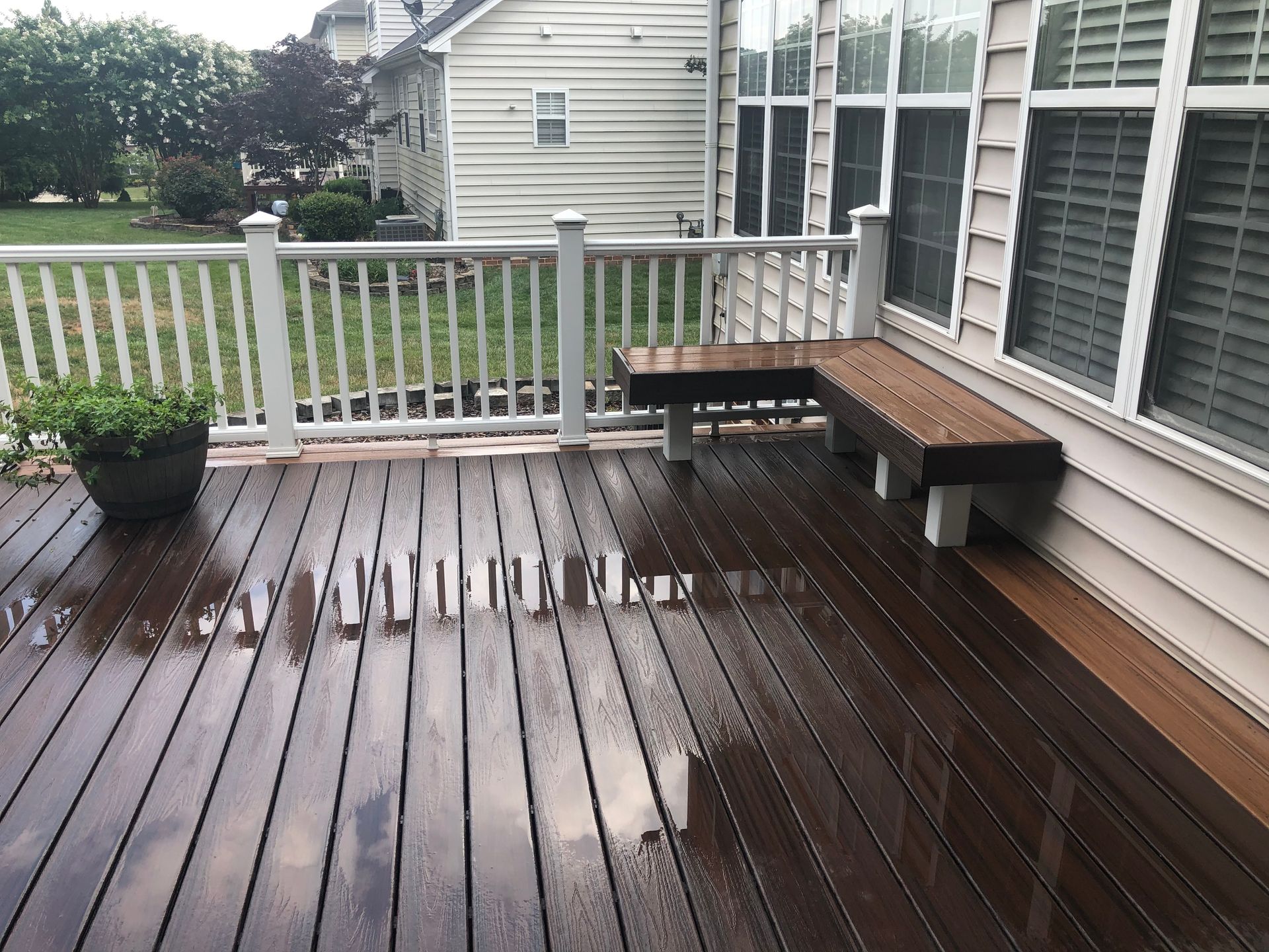 A wooden deck with a white railing and a bench