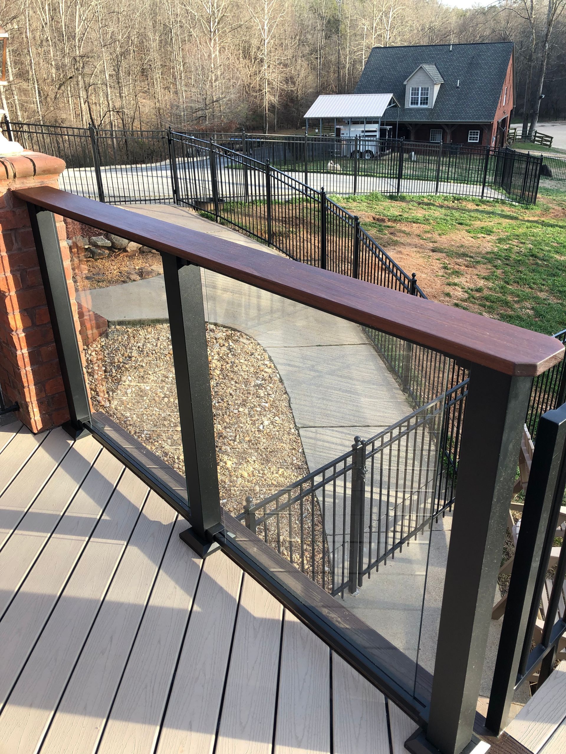 A deck with a glass railing and stairs leading to a house.
