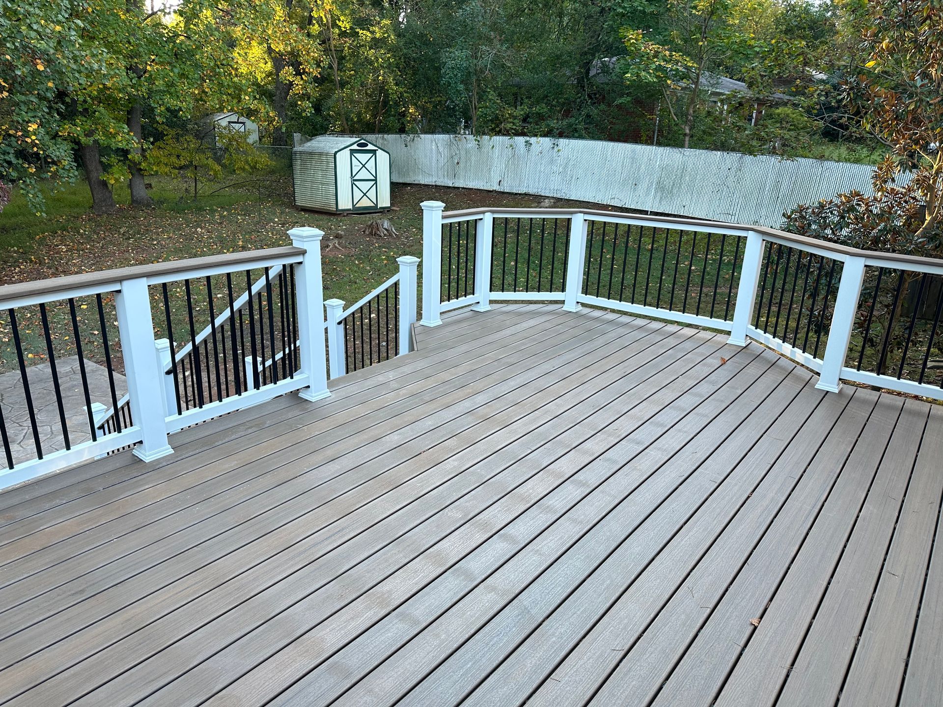 A wooden deck with a white railing and stairs leading up to it.