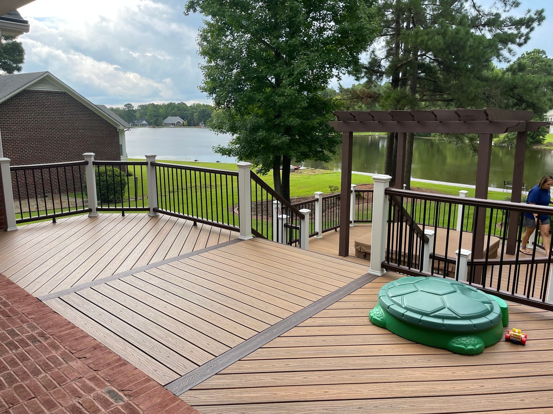 A man is standing on a deck overlooking a lake.