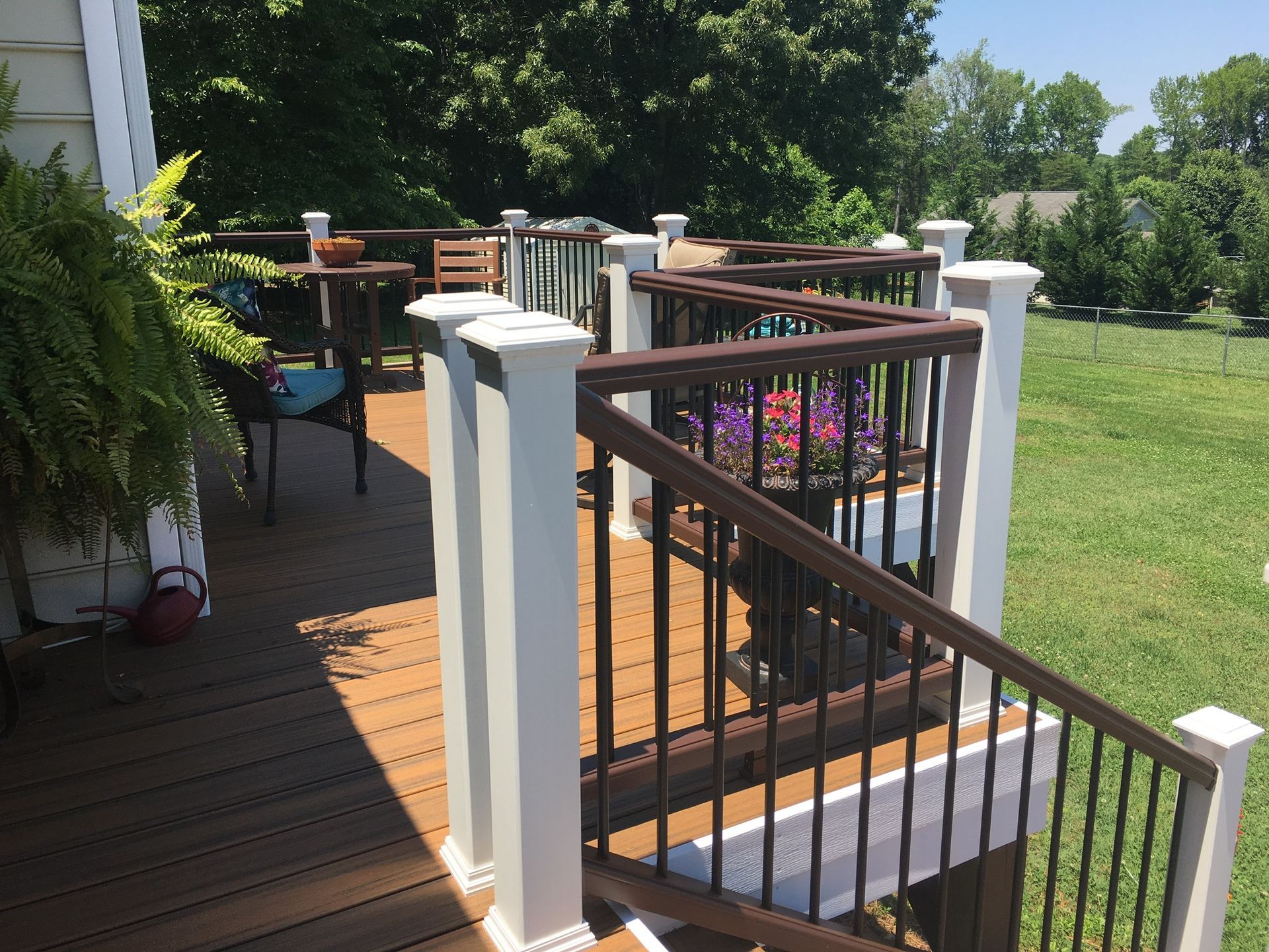 A wooden deck with a white railing and stairs leading up to it.