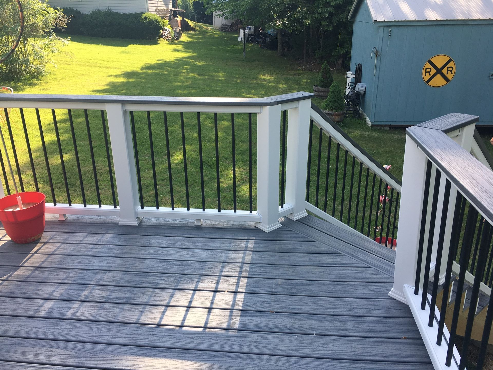 A wooden deck with a railing and a bucket on it.