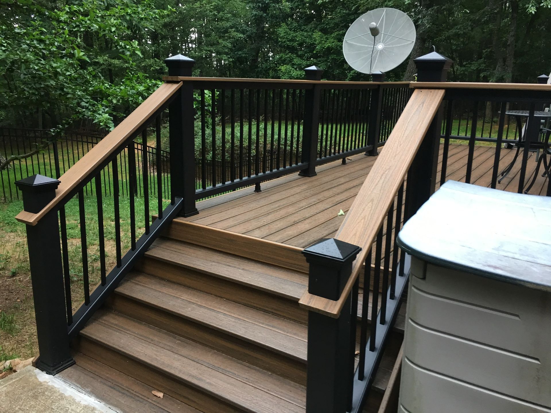 A wooden deck with stairs and a black railing