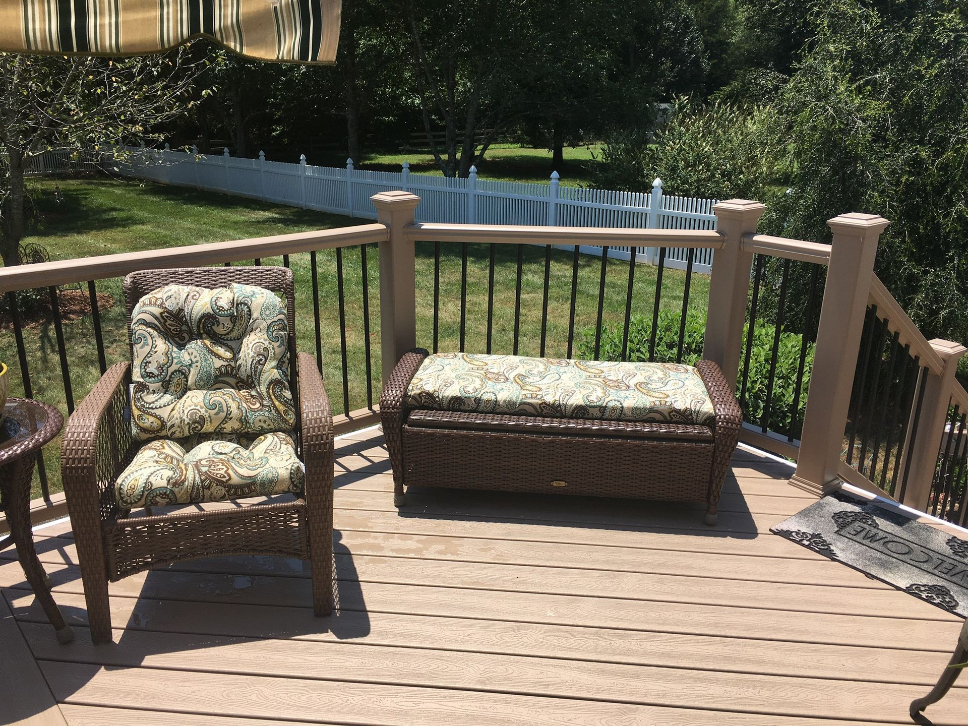 A deck with two chairs and an ottoman on it