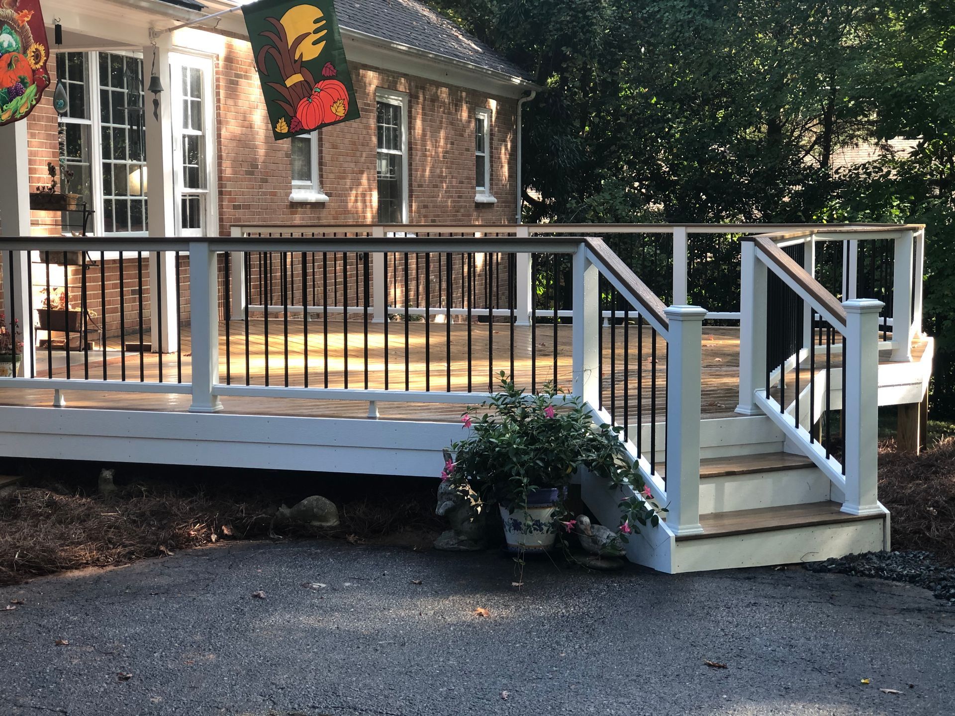 A large deck with stairs leading up to it is in front of a brick house.