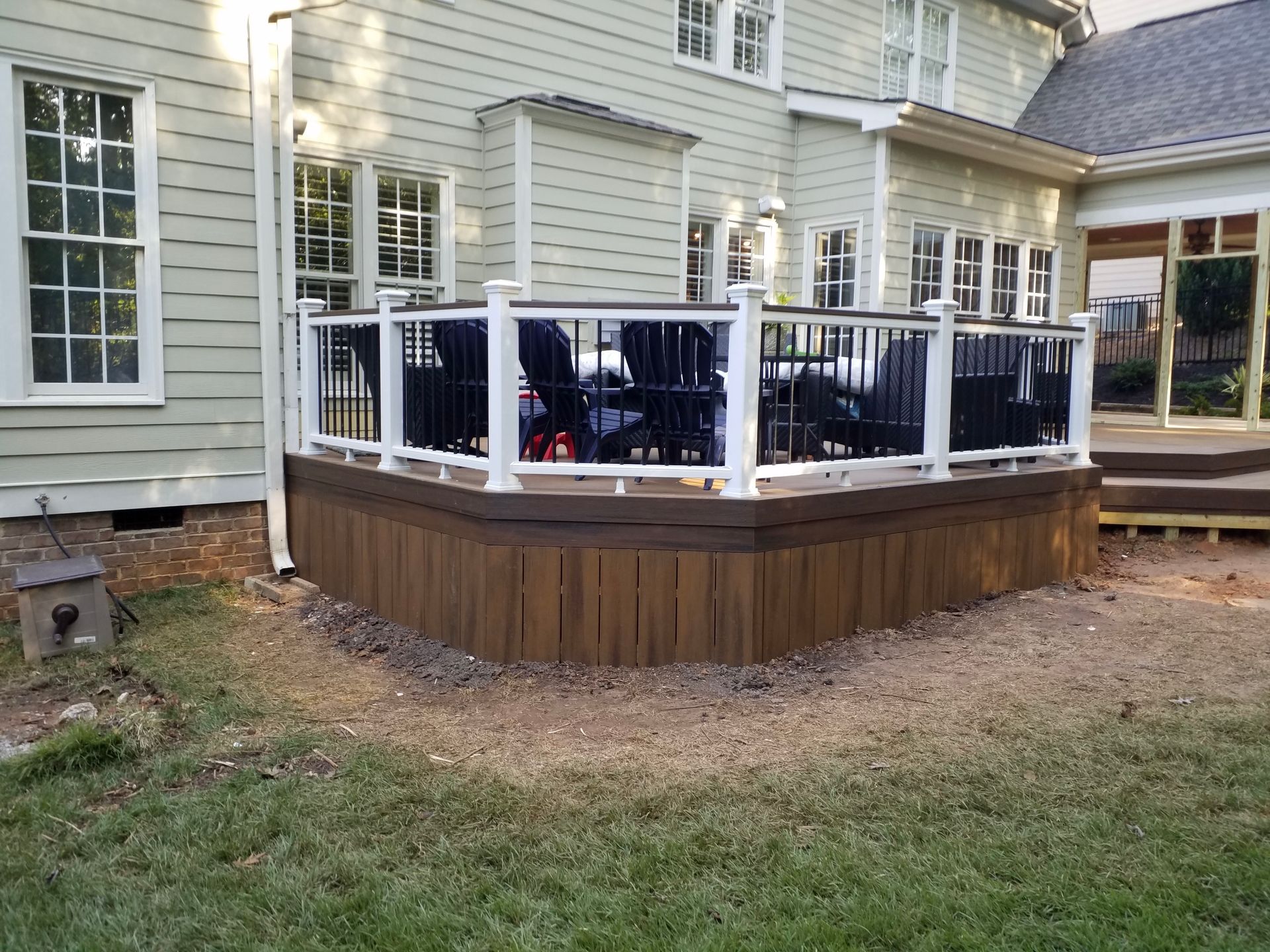 A wooden deck with a white railing is in front of a house.