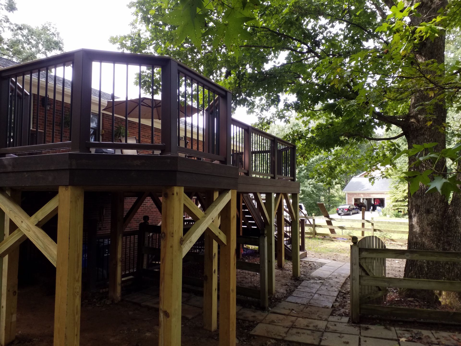 A wooden deck with stairs leading up to it is surrounded by trees.