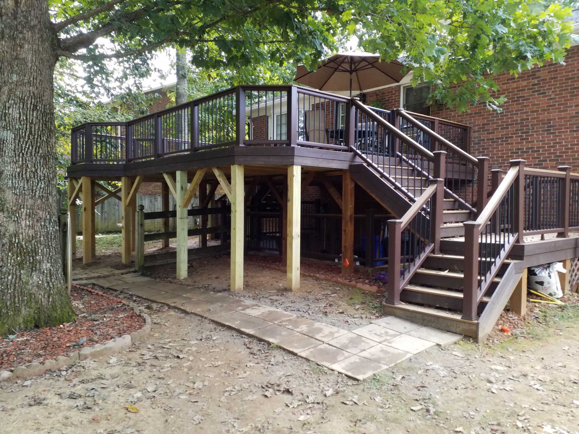 A large wooden deck with stairs and a tree in the background.
