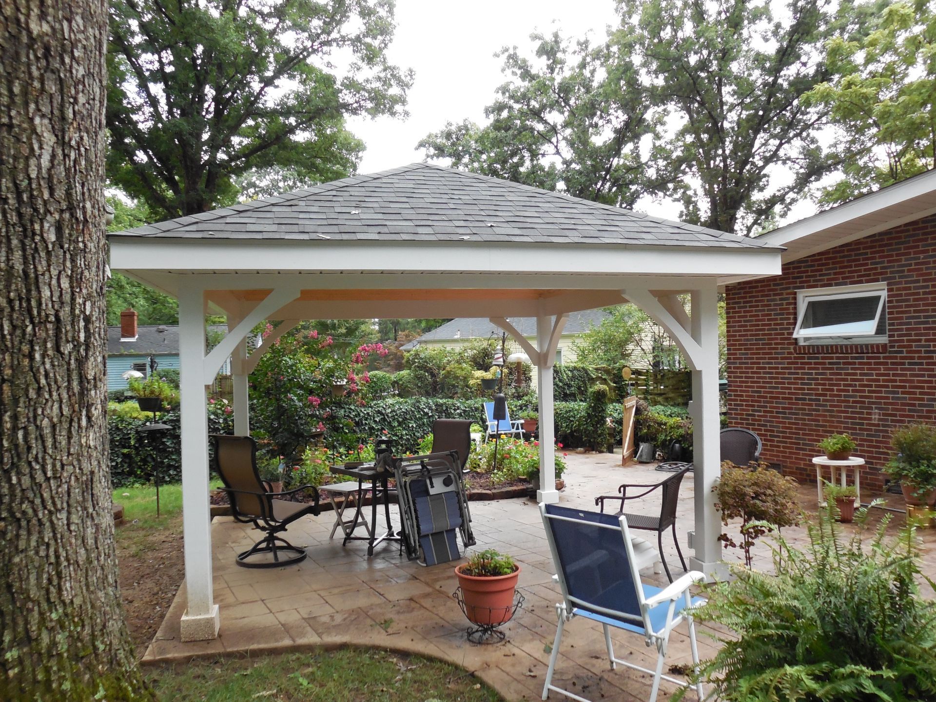 There is a gazebo in the backyard with chairs and tables underneath it.