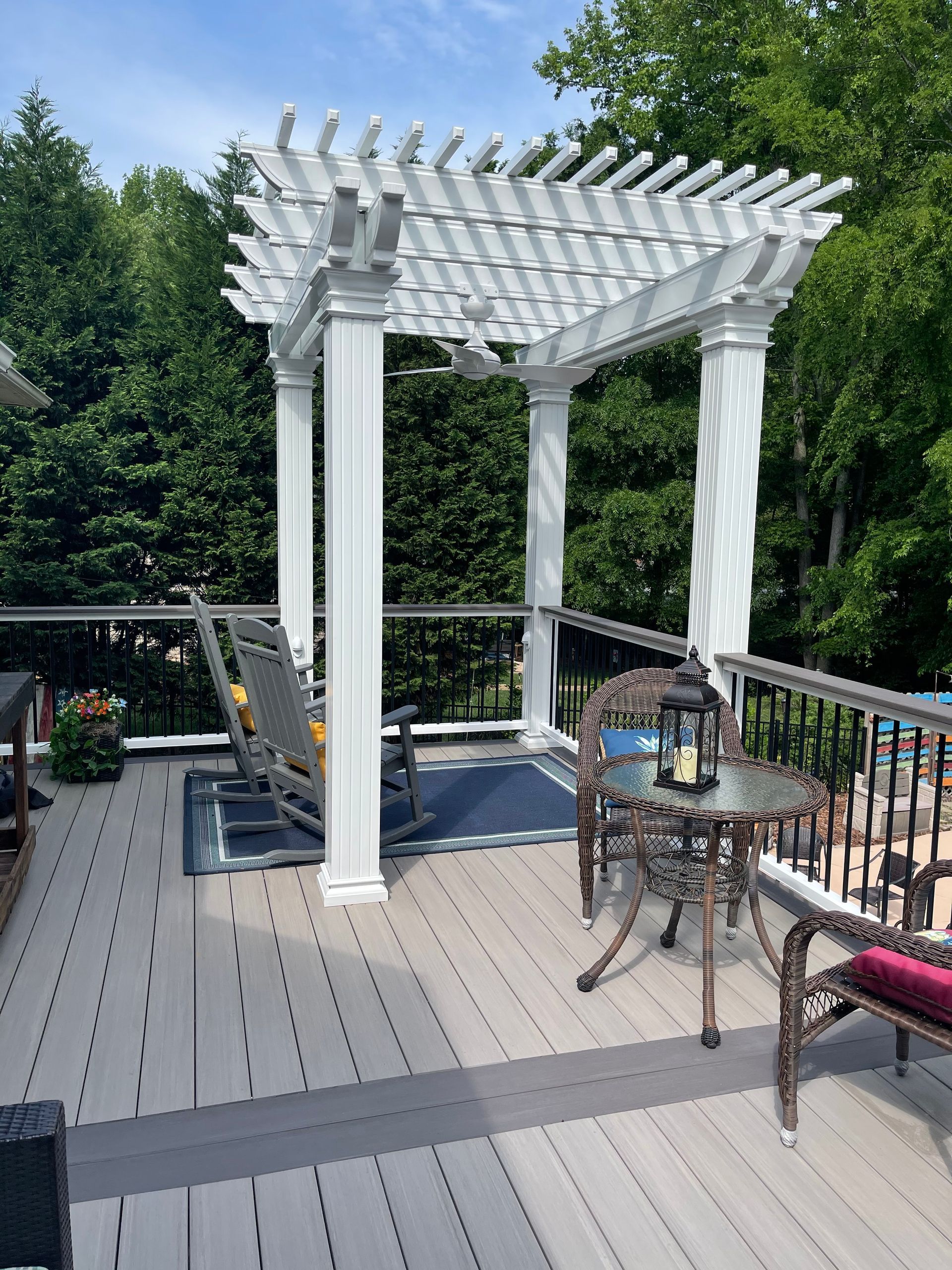 A deck with a pergola and chairs on it