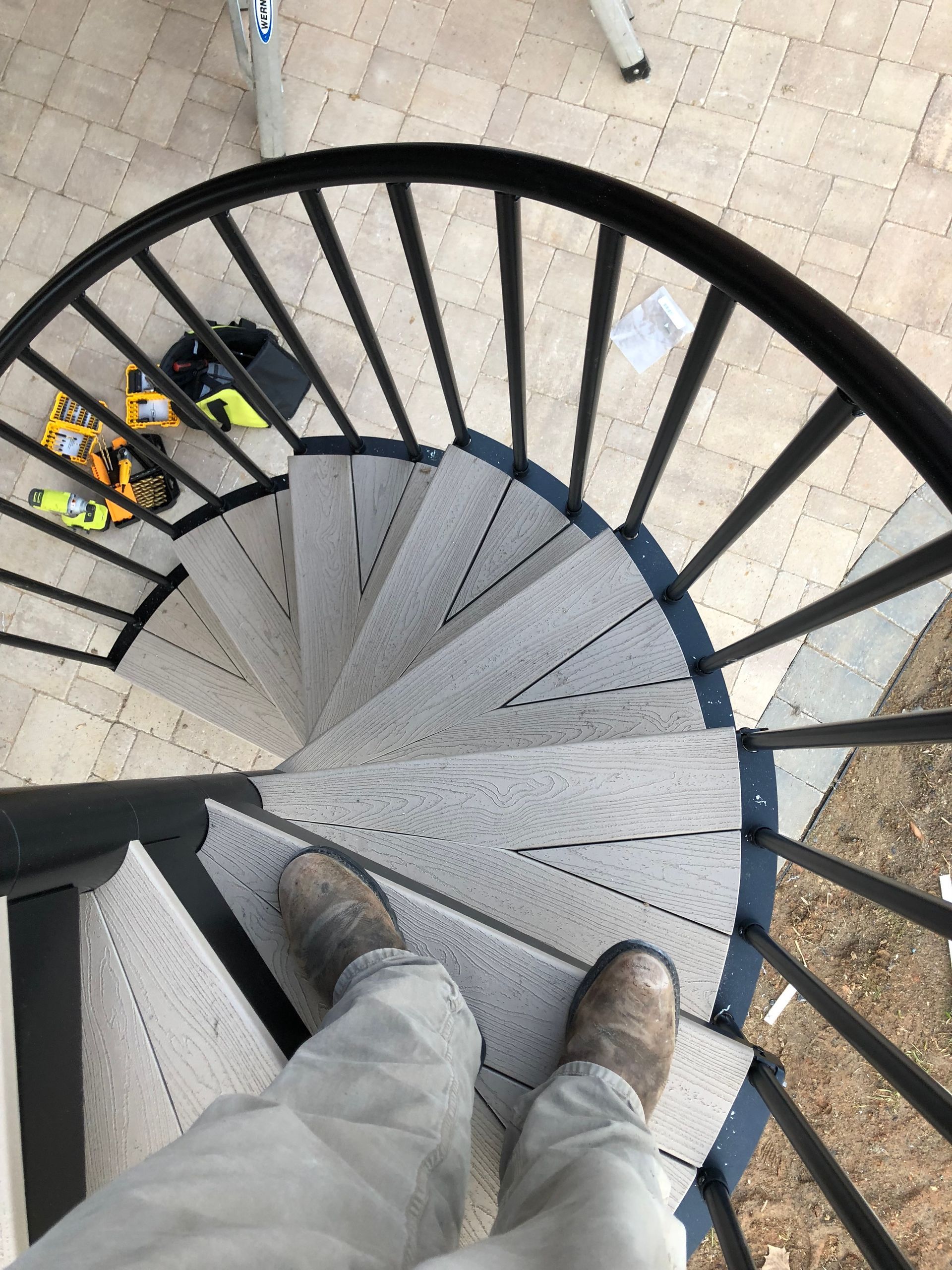 A person is standing on a spiral staircase with a black railing