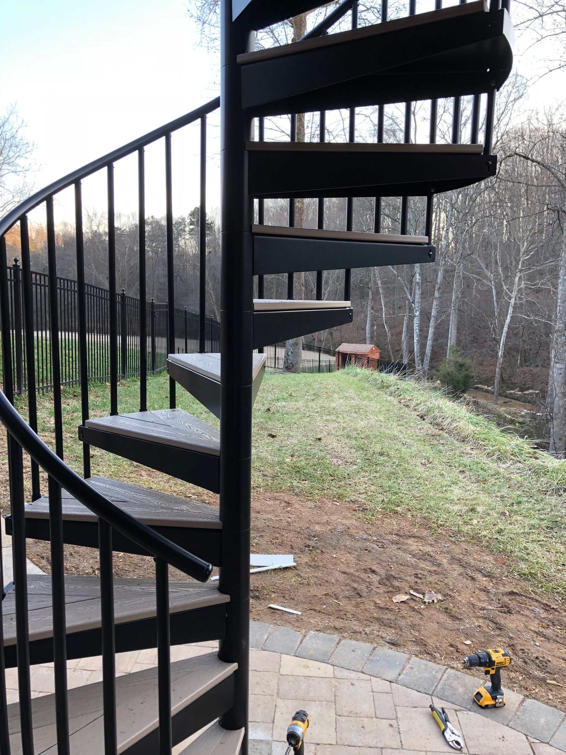 A spiral staircase is being built in a backyard.