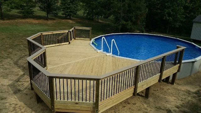 A wooden deck overlooking a swimming pool in a backyard.