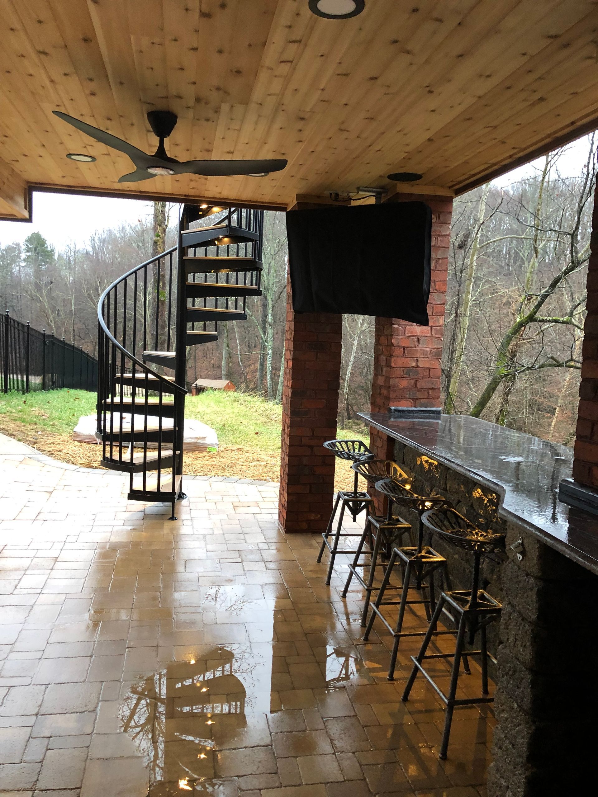 A patio with a spiral staircase and a flat screen tv