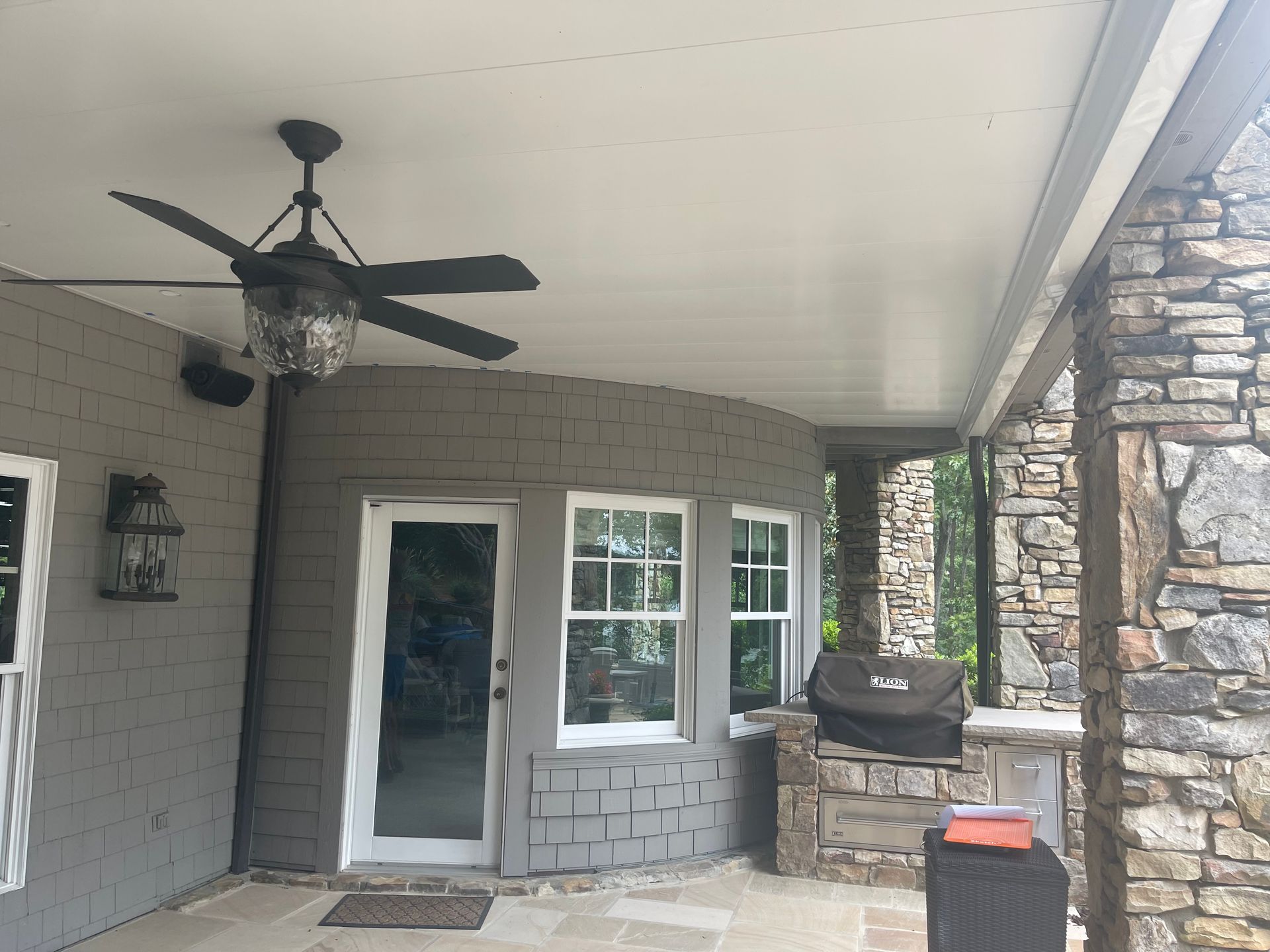 A porch with a ceiling fan and a grill
