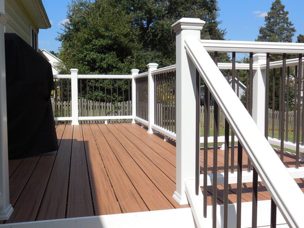 A wooden deck with a white railing and stairs