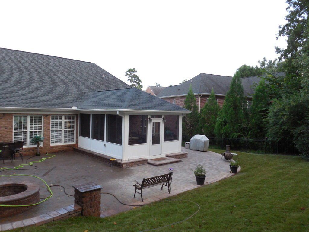 The backyard of a house with a screened in porch and patio