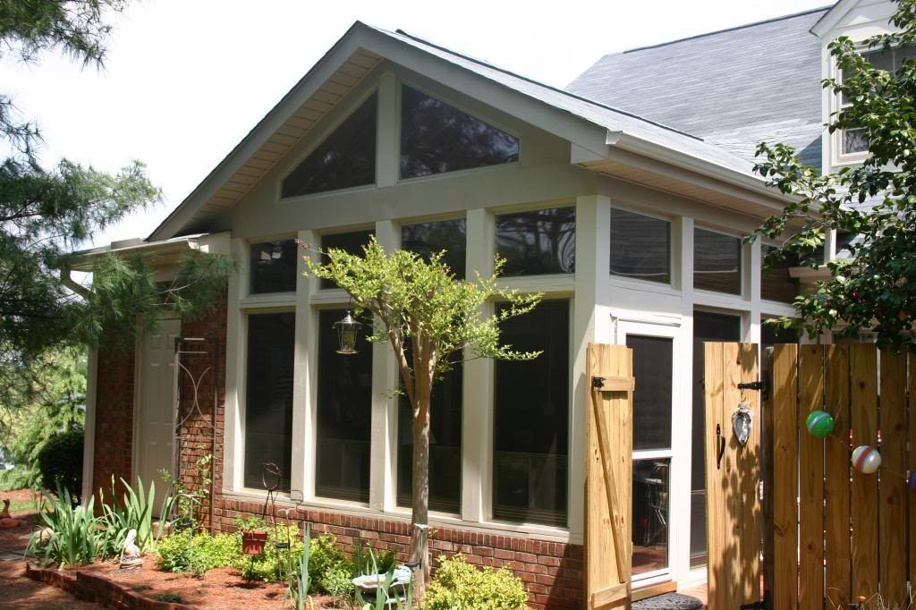 A house with a screened in porch and a wooden fence