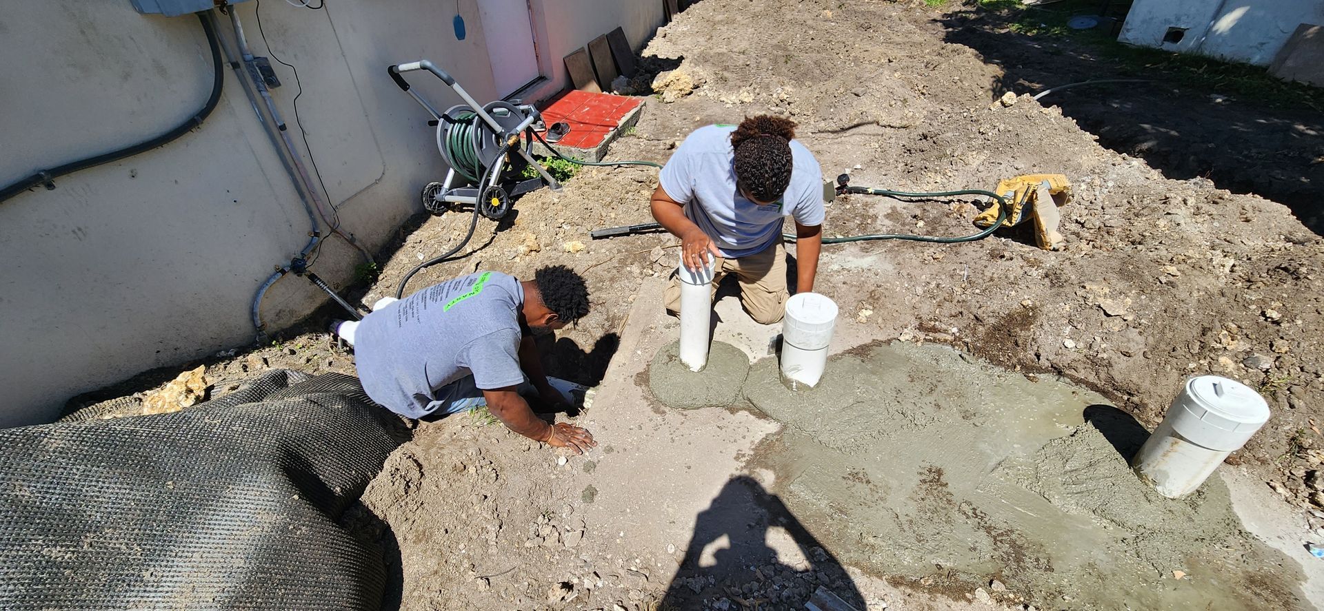 Two workers mix cement on a construction site.