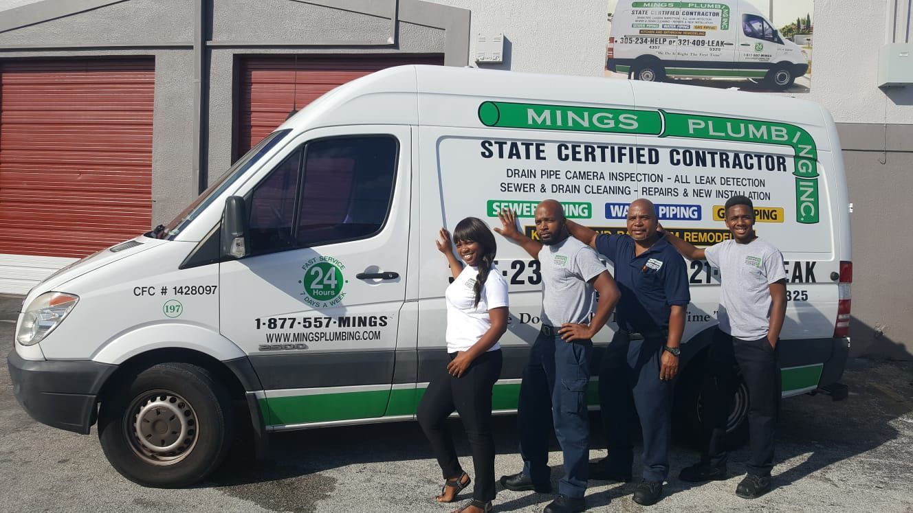 Four people pose in front of a white van.