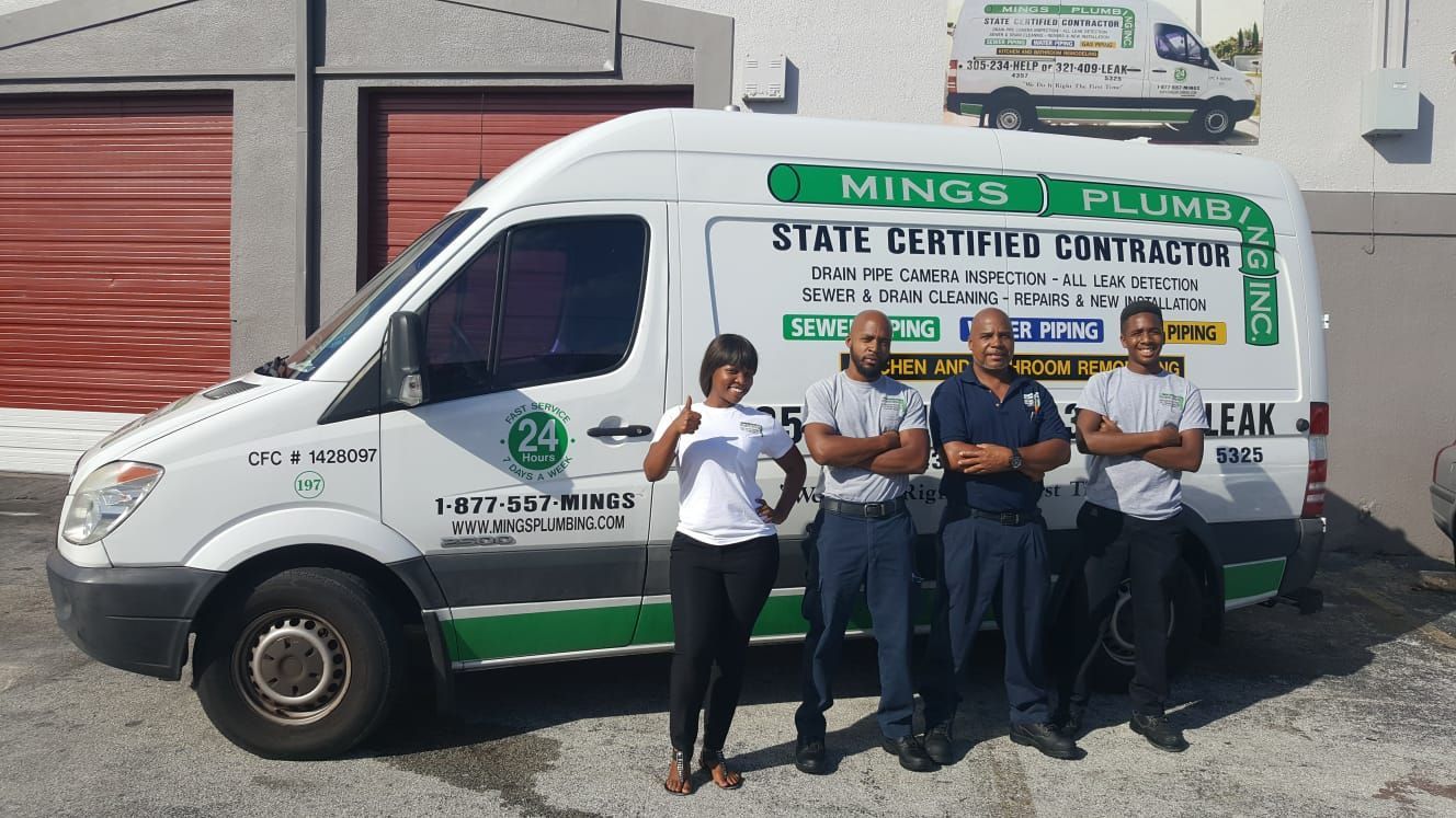 White van with Ming's Plumbing branding and a group of four people standing in front of it.