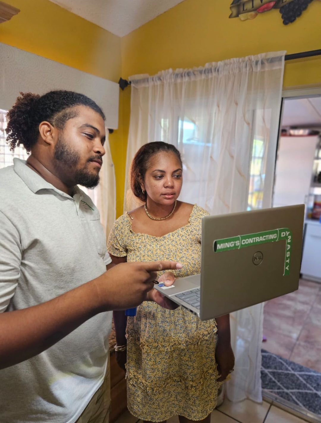 Two people looking at a laptop indoors; one points.