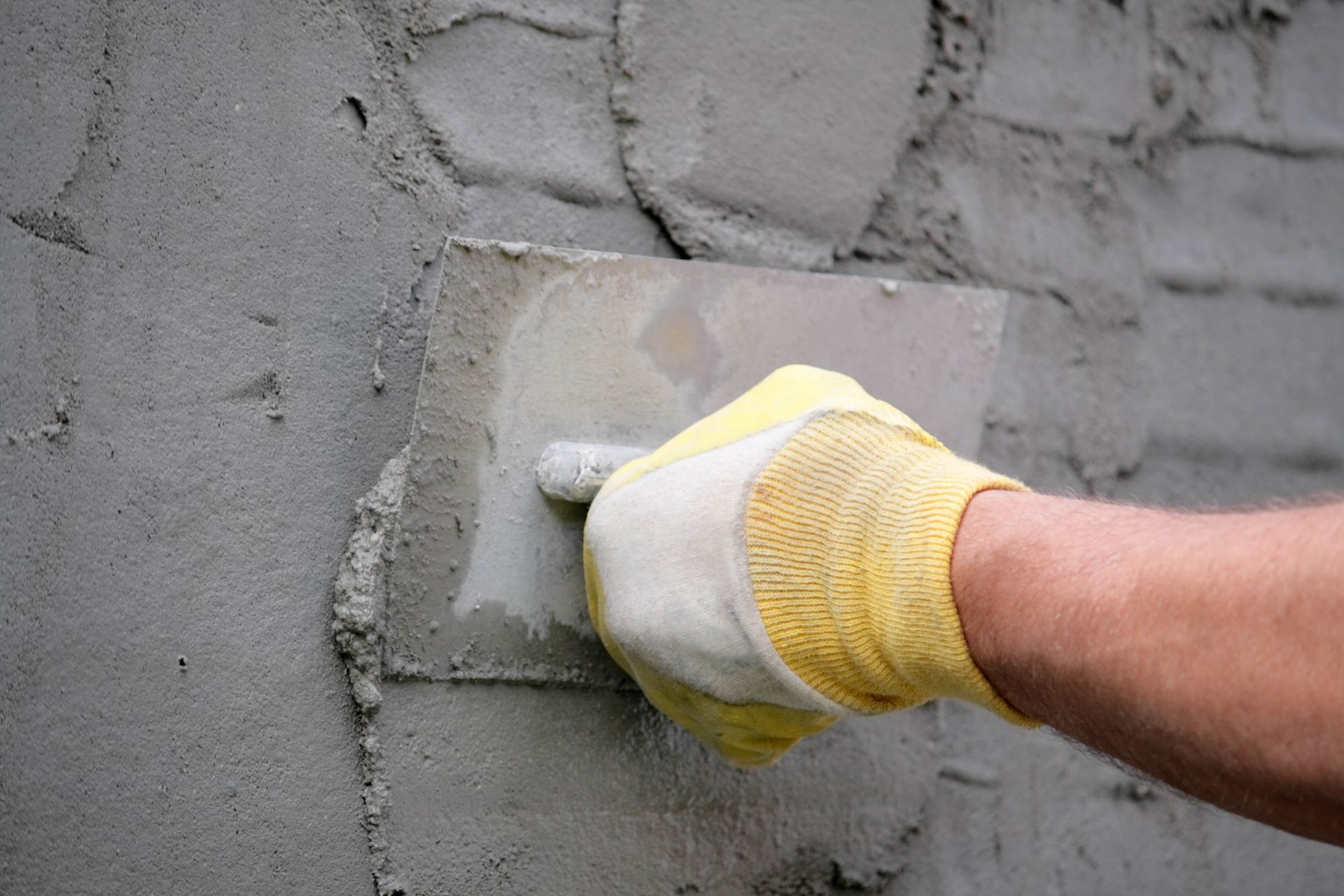 hand applying stucco on wall
