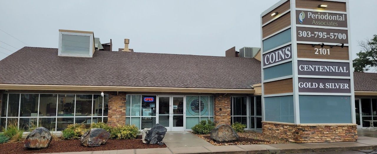 Exterior view of a commercial building with signage for Coins Centennial Gold & Silver and a dental practice.