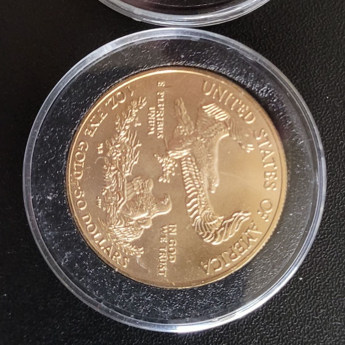 Gold coin inside a protective plastic case. Inscriptions include 