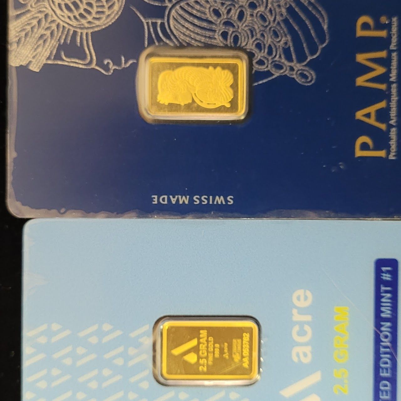 Two gold bullion bars in protective packaging, on blue cards. 