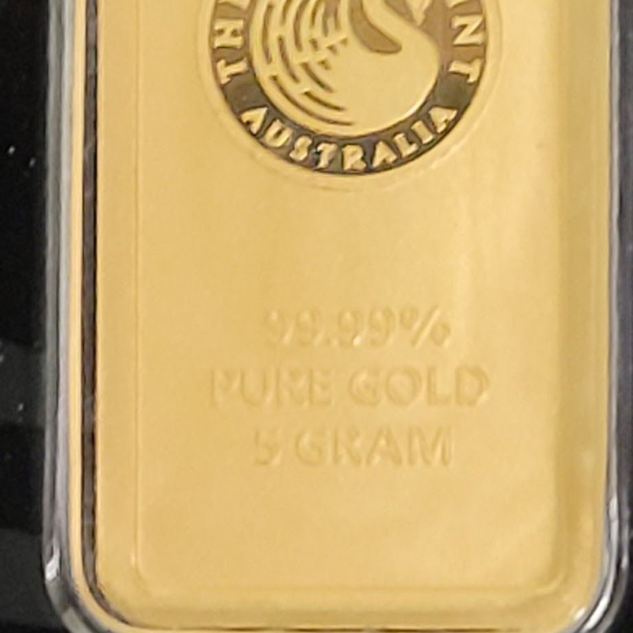 Gold bar encased in plastic, stamped with purity and weight details.