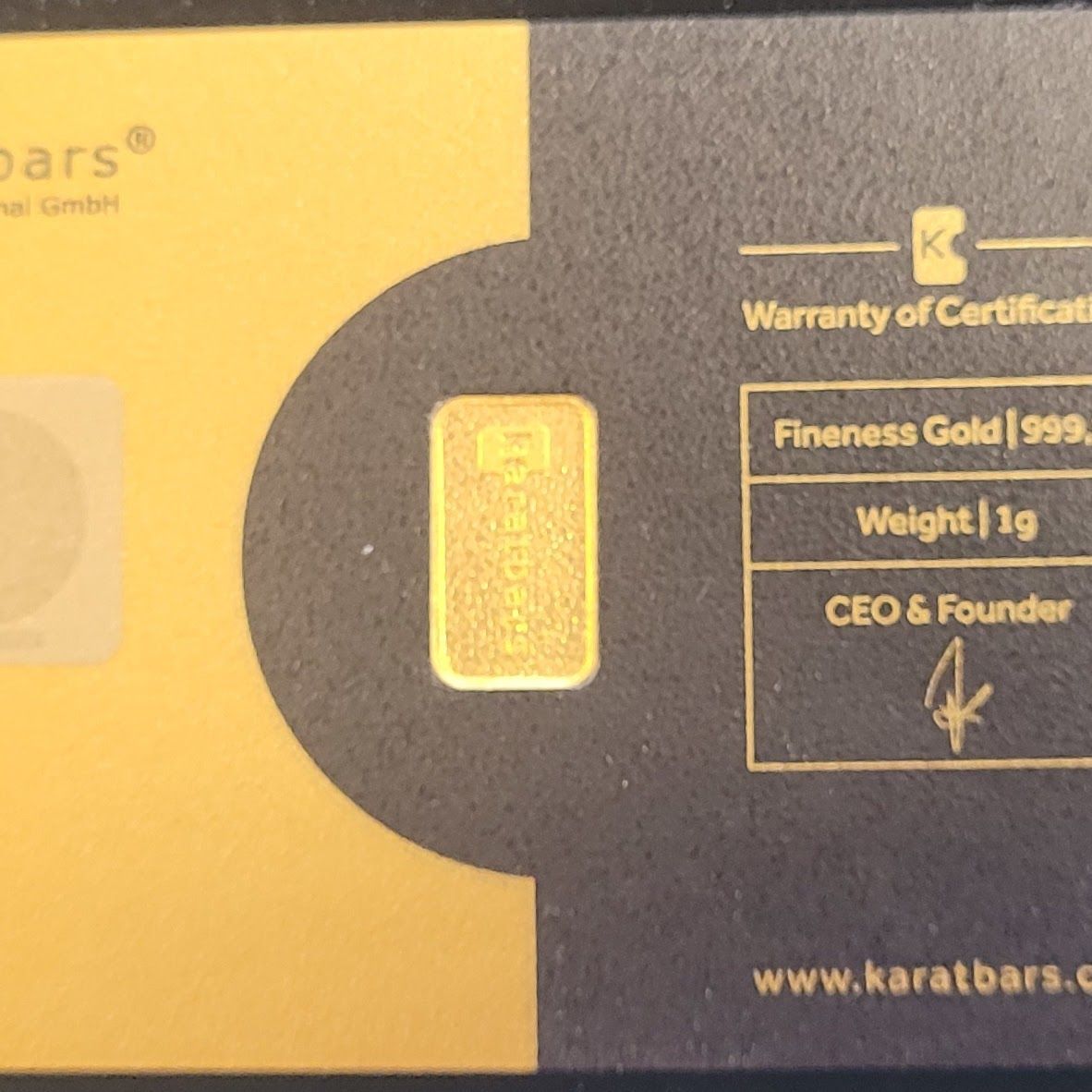 Gold bar inside a black and gold display card, stamped with weight and fineness.