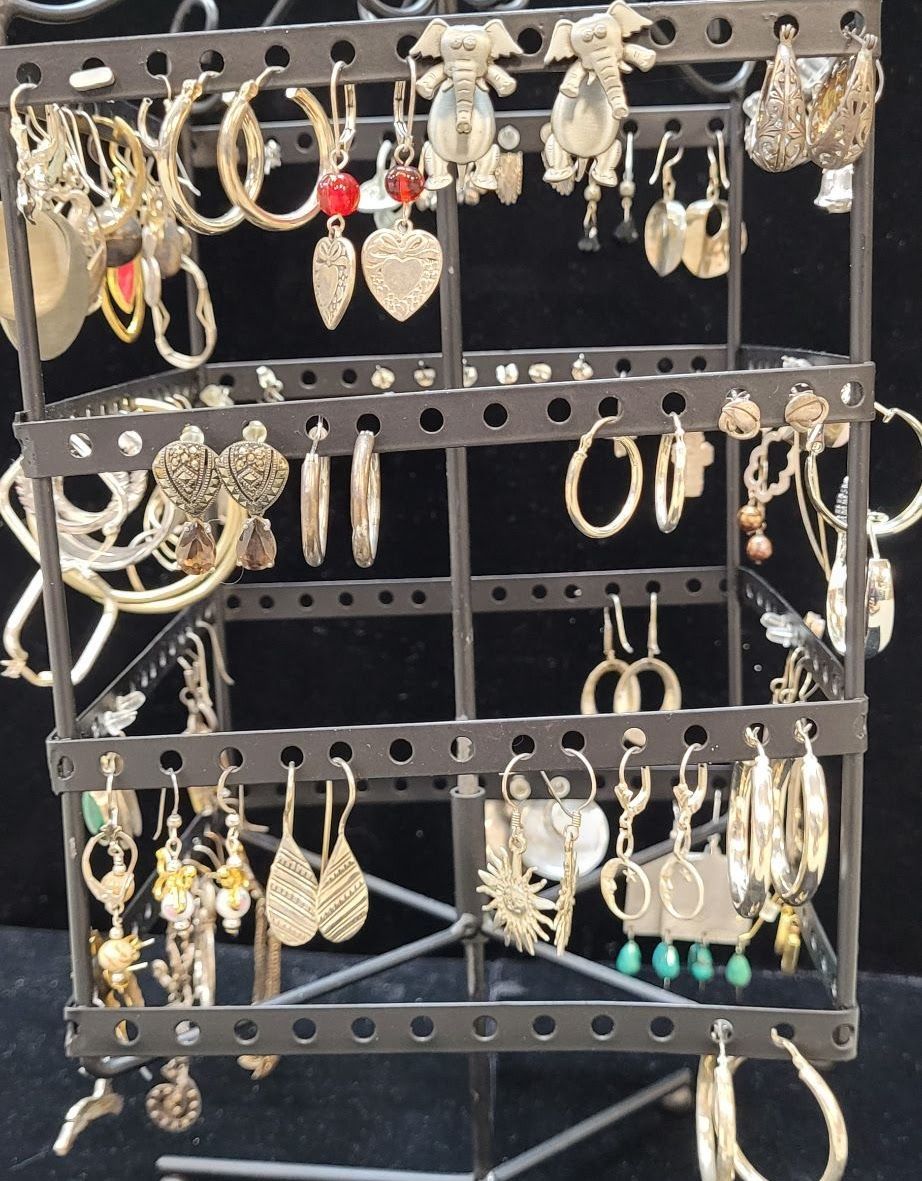 Earring display stand with various gold-toned earrings, set against a black background.