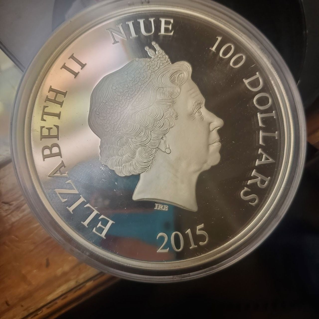 Silver coin, obverse. Queen Elizabeth II profile, text: Niue 100 Dollars, 2015.
