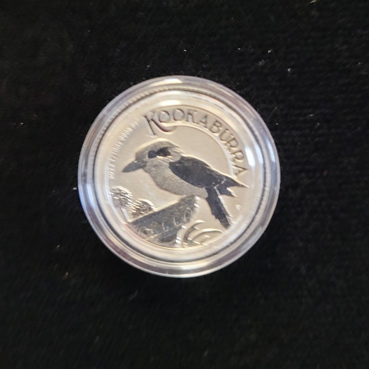 Silver coin, “Kookaburra” design: bird perched on a rock, in a protective plastic case.