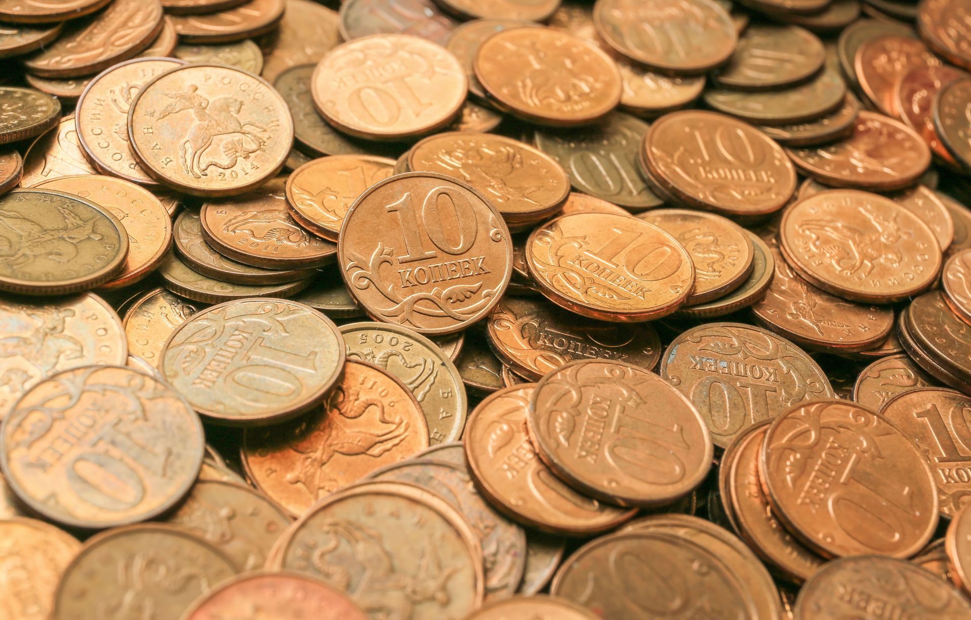 Pile of gold-colored coins, some with visible markings and numbers.