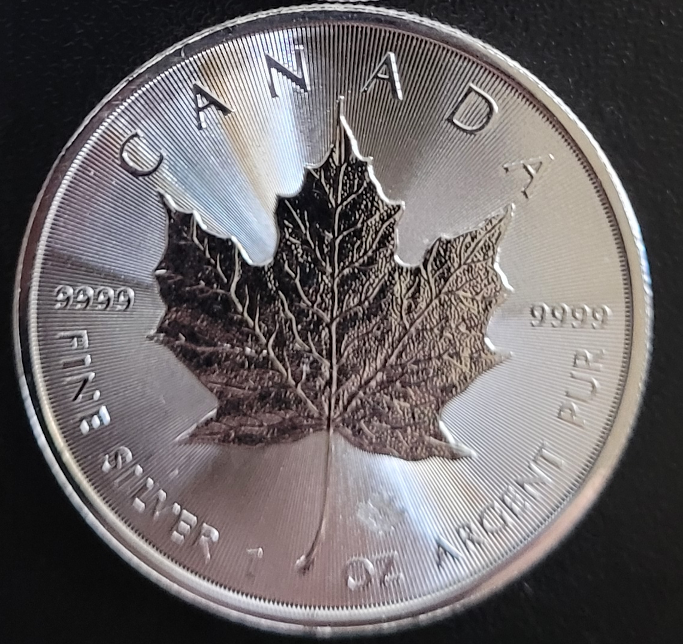 Silver Canadian Maple Leaf coin with engraved maple leaf.