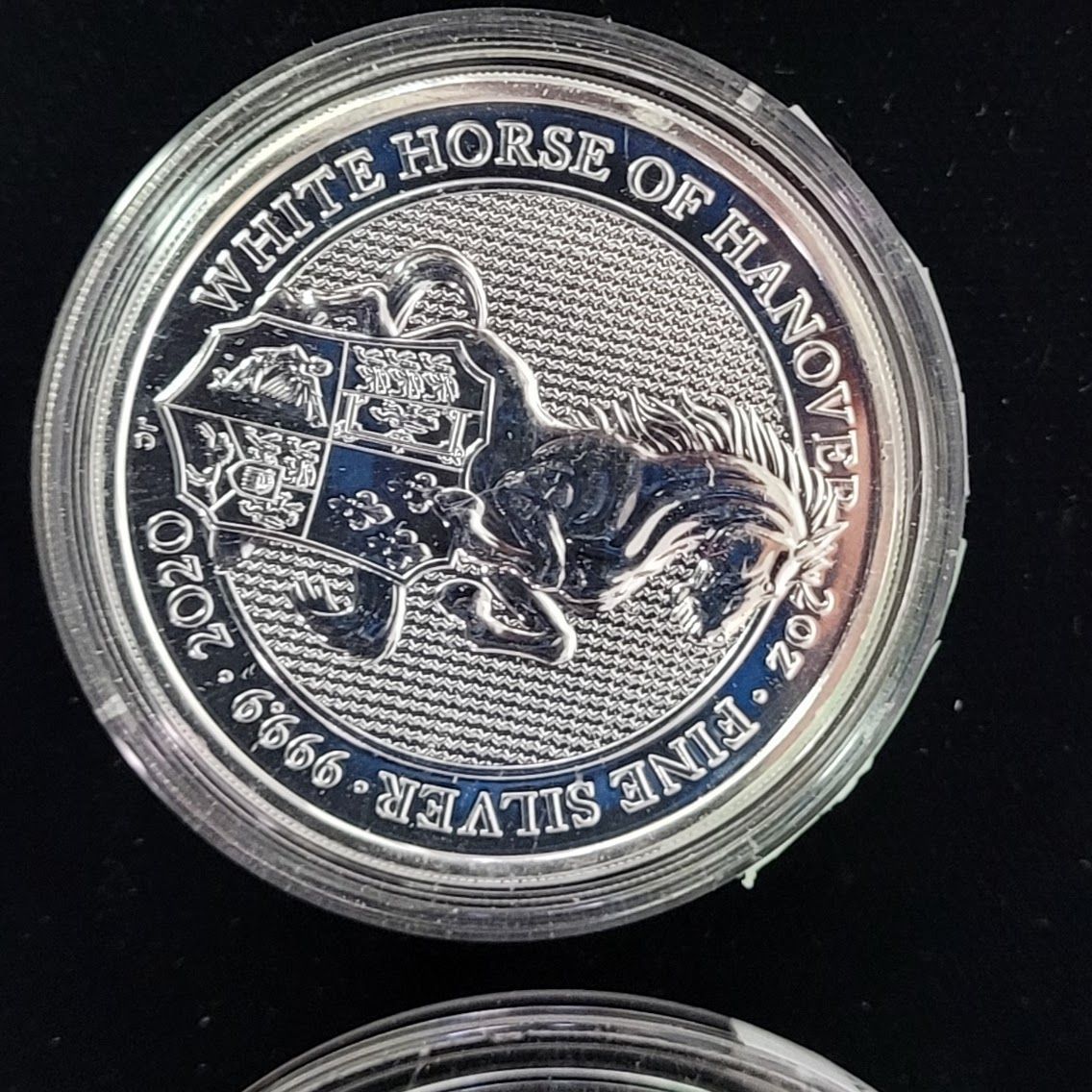 Silver coin featuring a rearing white horse, text: 