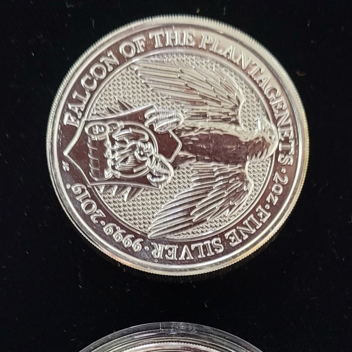 Silver coin with a detailed falcon design and text 