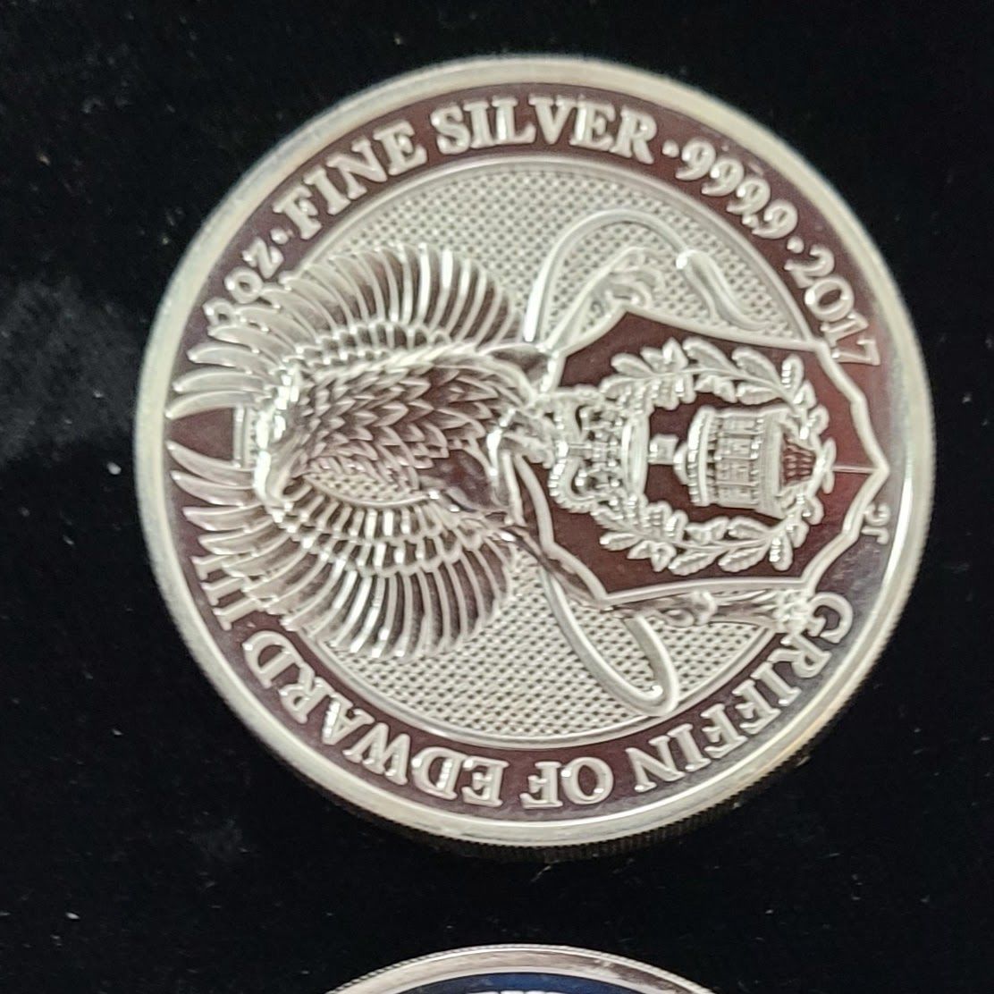 Silver coin with a griffin design, and text 
