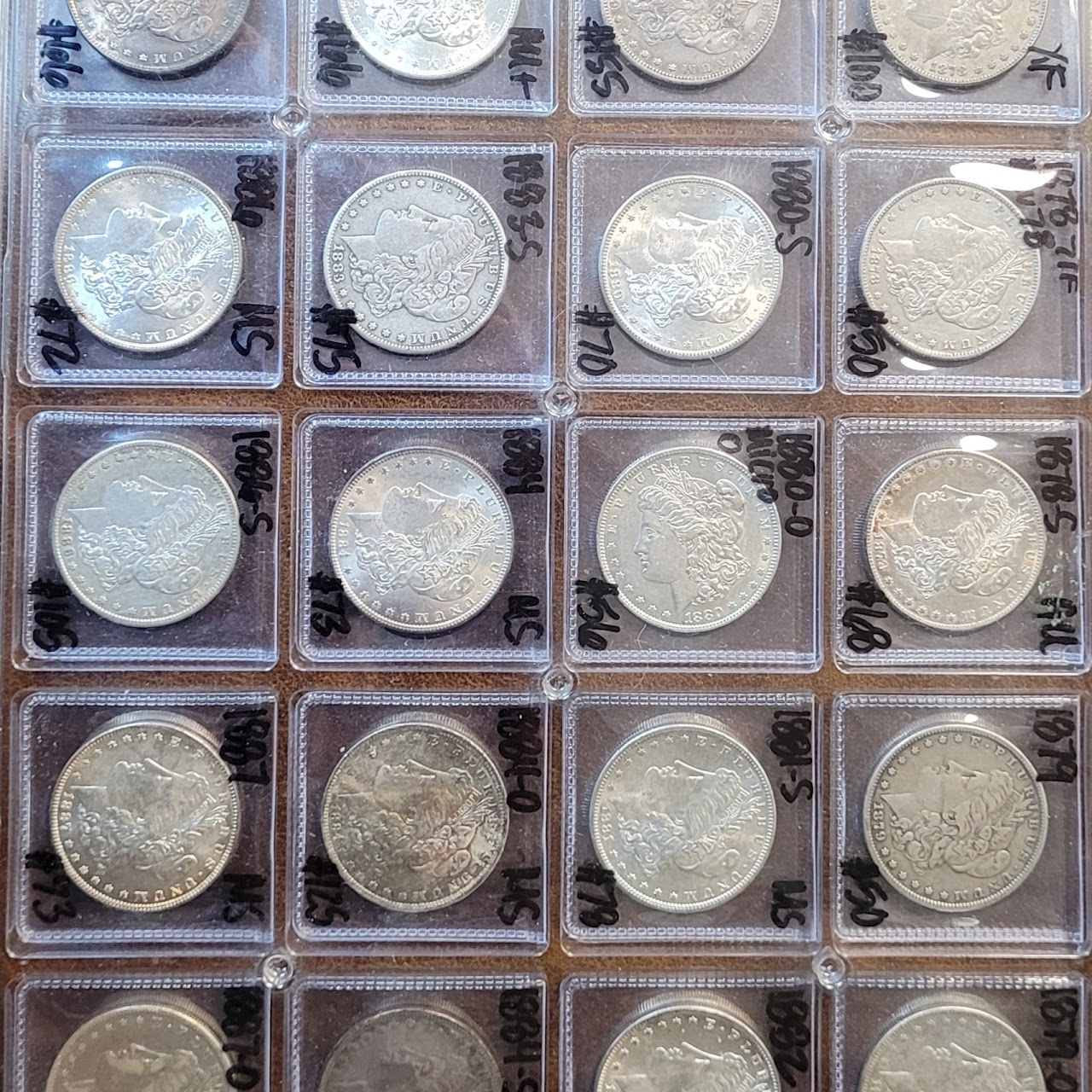 Collection of silver coins in plastic sleeves, displaying dates and grades.