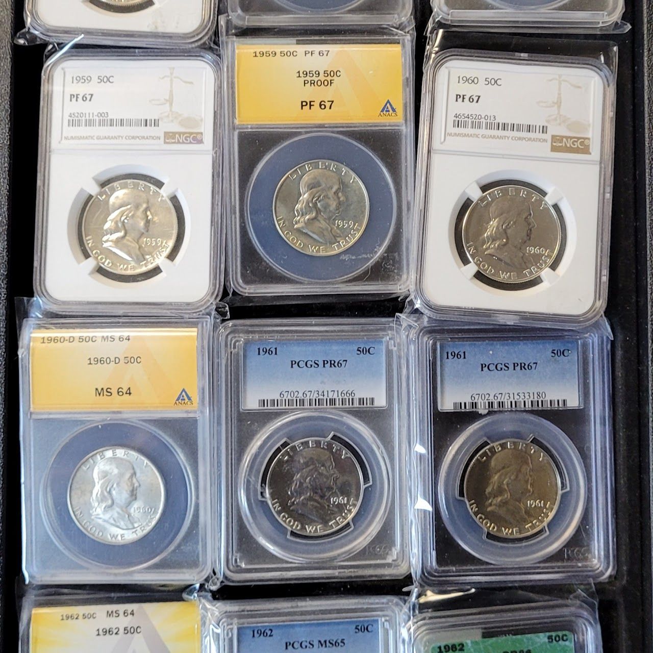Rows of encased coins in clear plastic, varying in color and size. Grading labels visible.