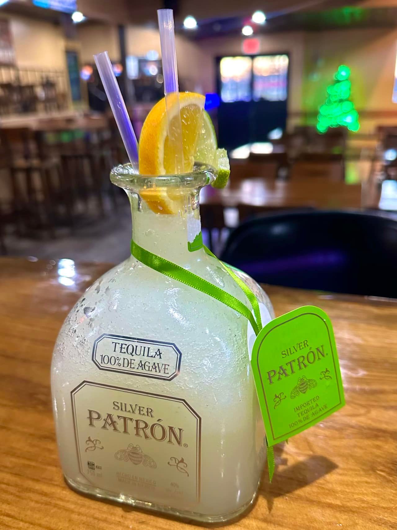 A bottle of patron tequila is sitting on a wooden table.