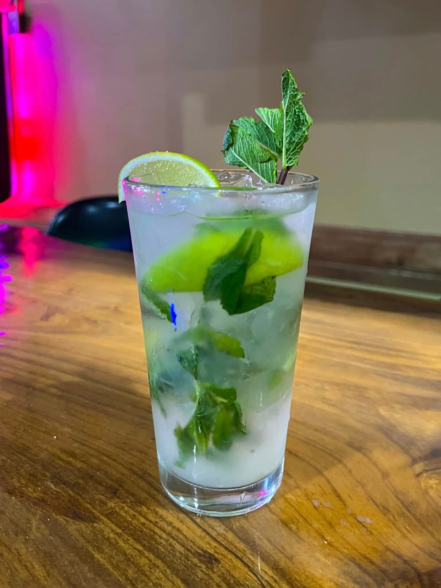 A glass of mojito with ice , mint and lime on a wooden table.