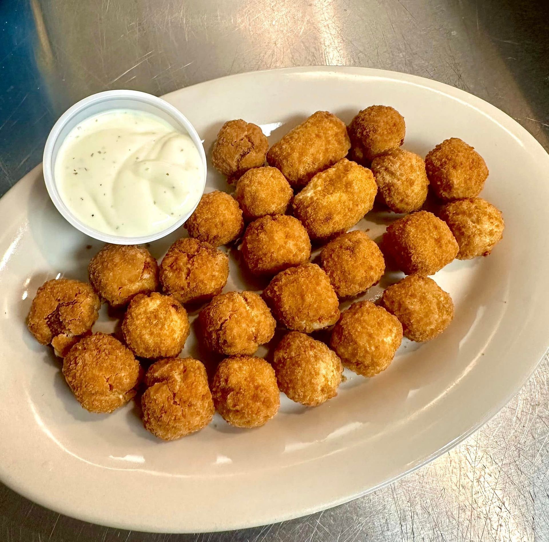 A white plate topped with fried food and a small bowl of ranch dressing