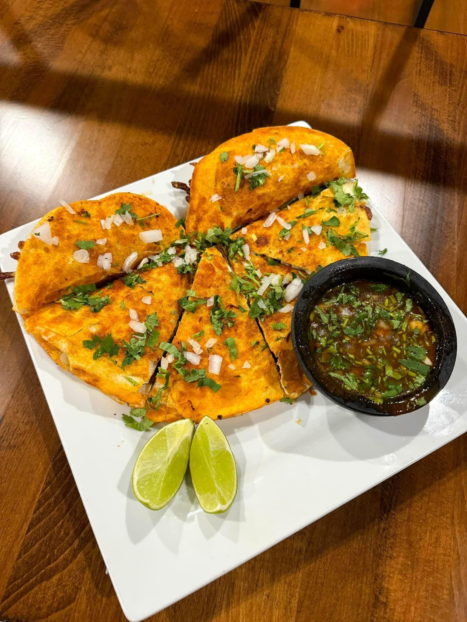 A white plate topped with tacos and salsa on a wooden table.