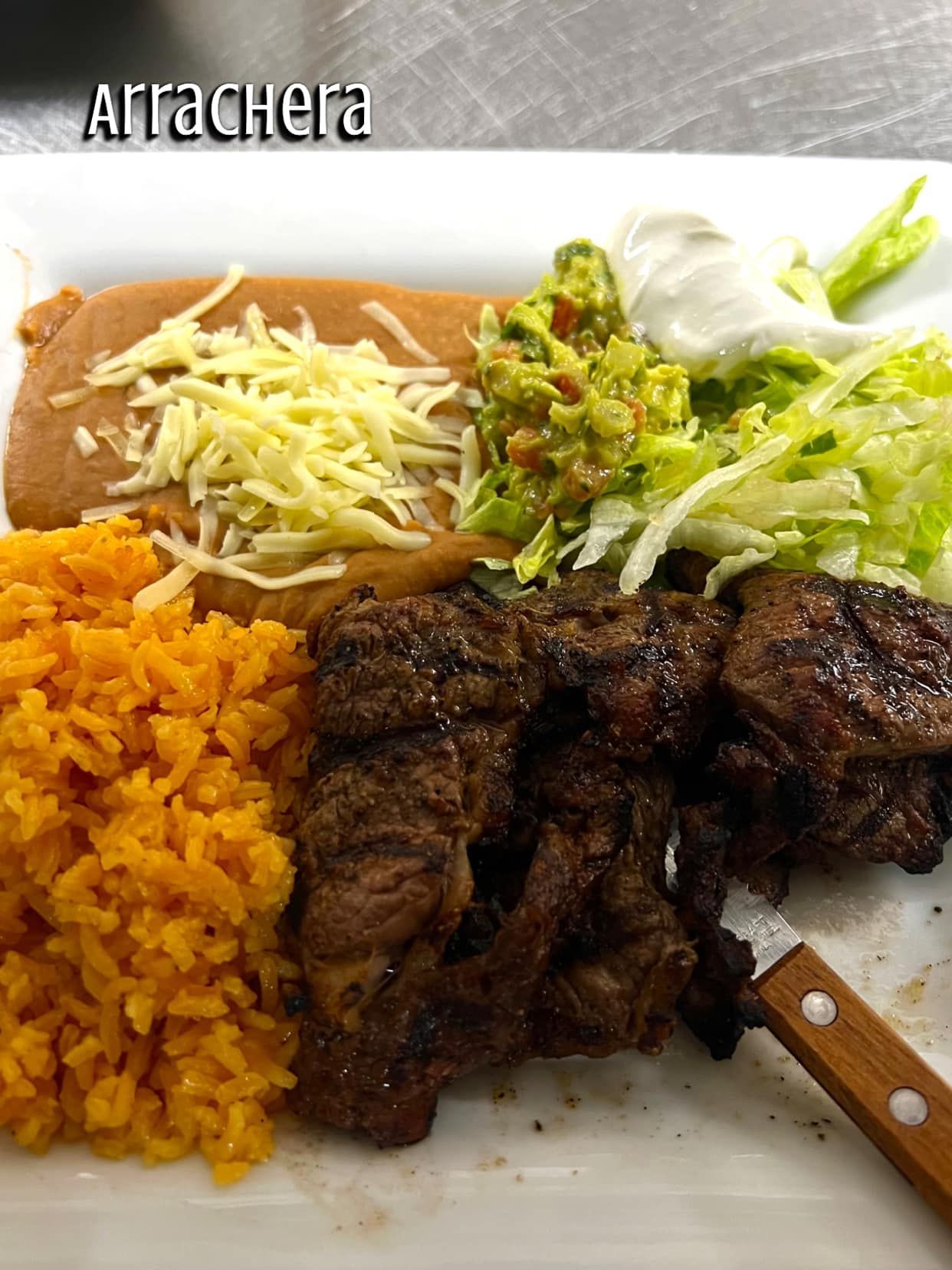 A white plate topped with rice , meat , guacamole and lettuce.