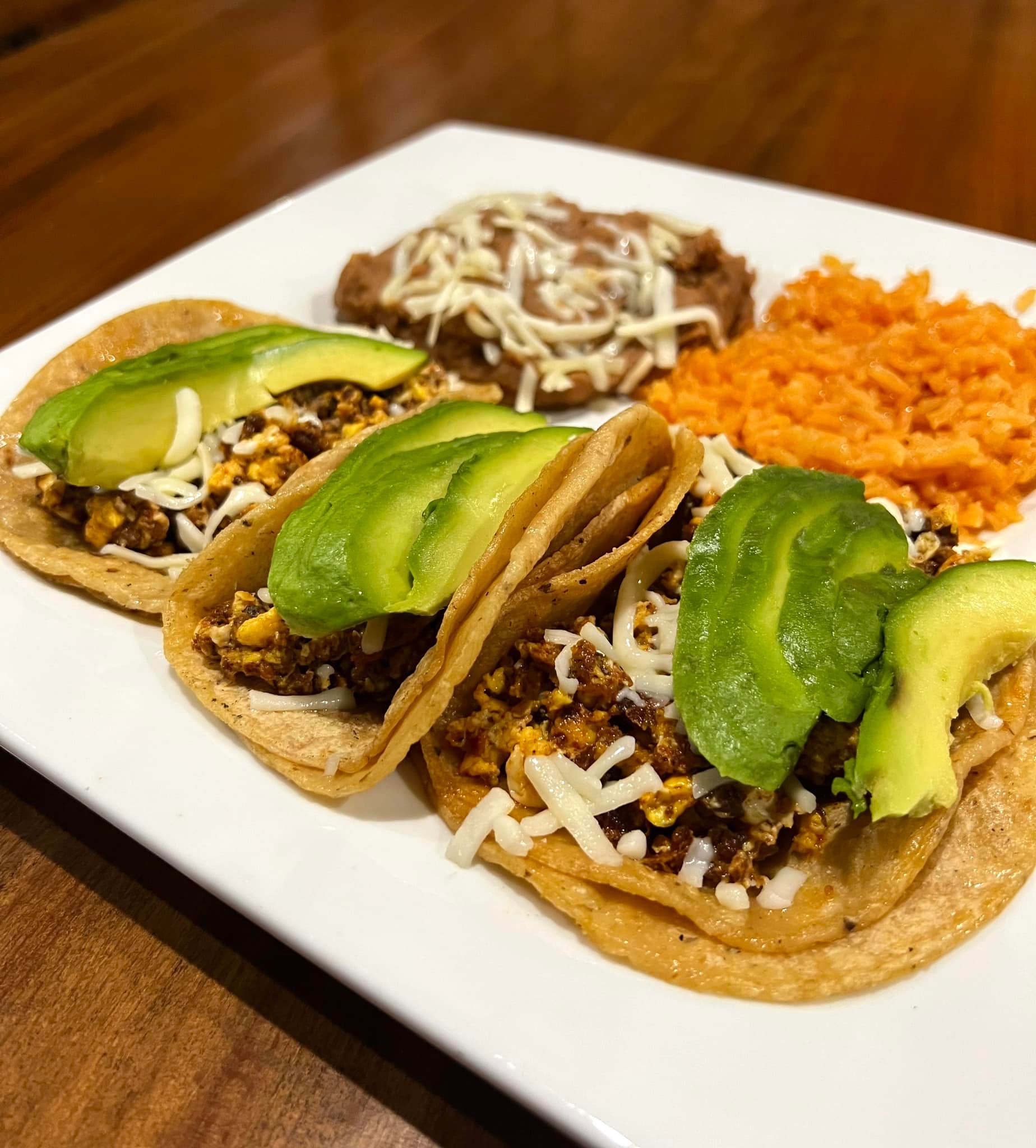 A white plate topped with tacos , rice and beans.