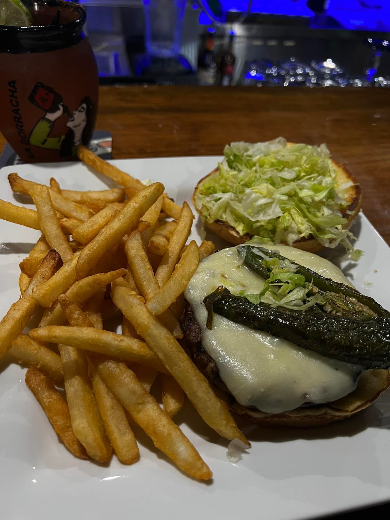 A hamburger and french fries on a white plate on a table.