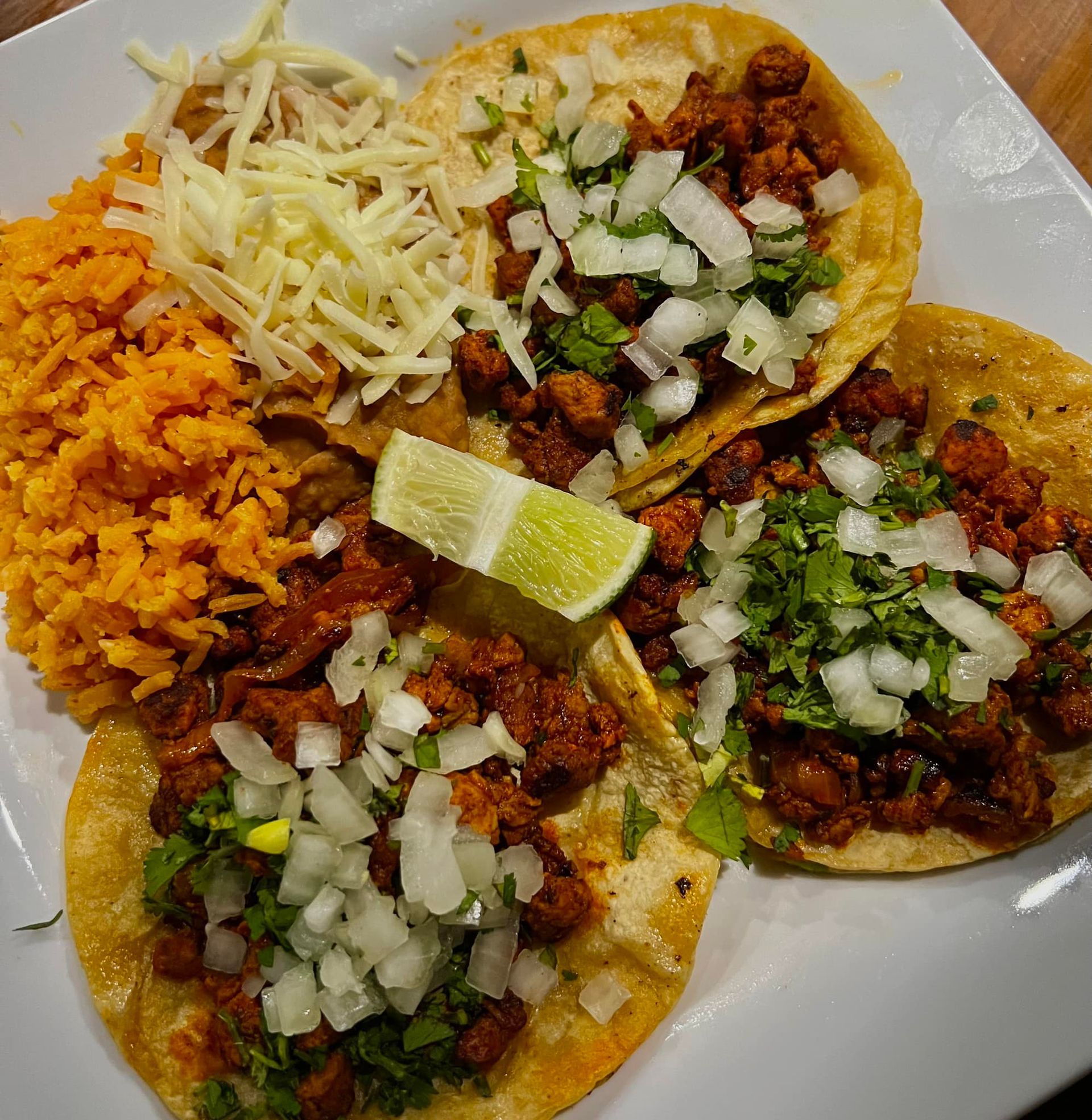 A white plate topped with tacos rice and cheese